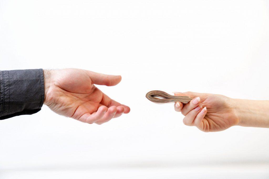 Bribery. A man’s hand in a black shirt takes a bribe from a woman’s hand. Side view. White background. The concept of the world anti-corruption day, 9